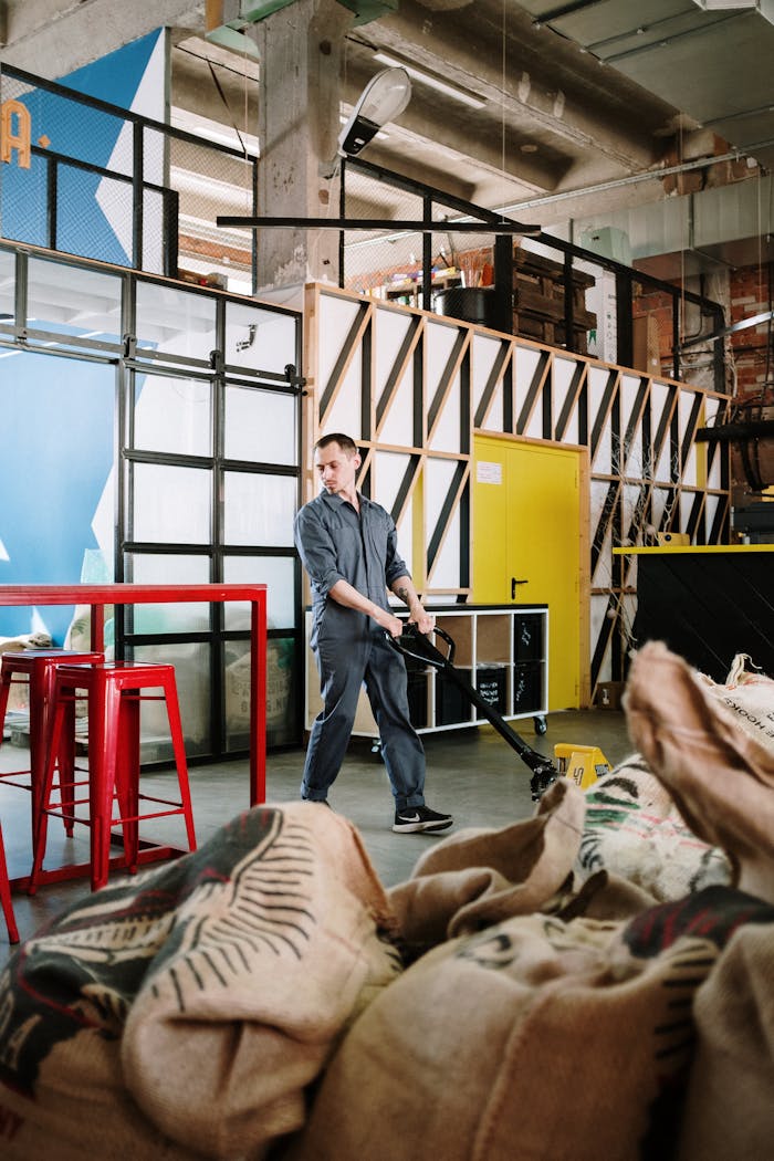 Man in uniform operating a trolley in a modern industrial warehouse with coffee sacks.
